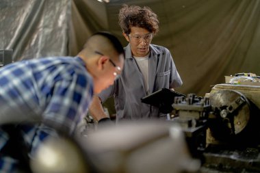 Adamlar makine yerleştirmek için çelik parçaları inceliyor. Öğretmen ve öğrenci takımı çelik fabrikasında ağır makineler kullanmayı öğreniyor. İşçiler üretim sırasında kalite kontrolü yaparken işbirliği yaparlar.