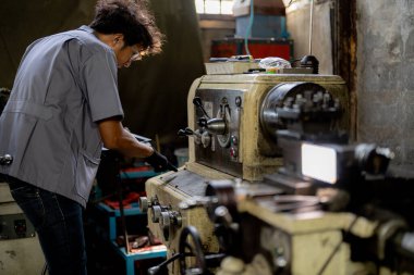 Fabrikada sondaj yapan Asyalı bir işçi. Fabrikadaki sondaj makinesinin yanında profesyonel işçi. Torna makinesinde uçan kıvılcımlarla çalışan metal iç çeliği bitirmek.