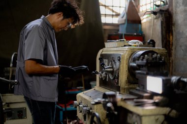 Fabrikada sondaj yapan Asyalı bir işçi. Fabrikadaki sondaj makinesinin yanında profesyonel işçi. Torna makinesinde uçan kıvılcımlarla çalışan metal iç çeliği bitirmek.