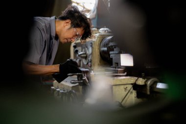 Fabrikada sondaj yapan Asyalı bir işçi. Fabrikadaki sondaj makinesinin yanında profesyonel işçi. Torna makinesinde uçan kıvılcımlarla çalışan metal iç çeliği bitirmek.