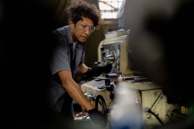 Fabrikada sondaj yapan Asyalı bir işçi. Fabrikadaki sondaj makinesinin yanında profesyonel işçi. Torna makinesinde uçan kıvılcımlarla çalışan metal iç çeliği bitirmek.