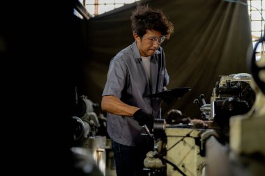 Fabrikada sondaj yapan Asyalı bir işçi. Fabrikadaki sondaj makinesinin yanında profesyonel işçi. Torna makinesinde uçan kıvılcımlarla çalışan metal iç çeliği bitirmek.