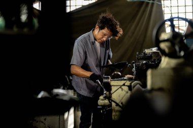 Fabrikada sondaj yapan Asyalı bir işçi. Fabrikadaki sondaj makinesinin yanında profesyonel işçi. Torna makinesinde uçan kıvılcımlarla çalışan metal iç çeliği bitirmek.