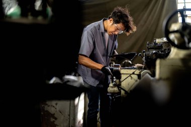 Fabrikada sondaj yapan Asyalı bir işçi. Fabrikadaki sondaj makinesinin yanında profesyonel işçi. Torna makinesinde uçan kıvılcımlarla çalışan metal iç çeliği bitirmek.