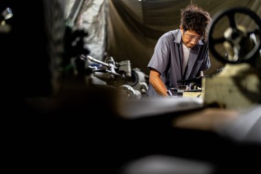 Fabrikada sondaj yapan Asyalı bir işçi. Fabrikadaki sondaj makinesinin yanında profesyonel işçi. Torna makinesinde uçan kıvılcımlarla çalışan metal iç çeliği bitirmek.