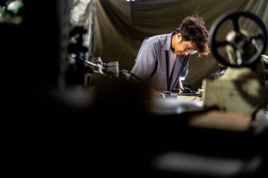 Fabrikada sondaj yapan Asyalı bir işçi. Fabrikadaki sondaj makinesinin yanında profesyonel işçi. Torna makinesinde uçan kıvılcımlarla çalışan metal iç çeliği bitirmek.