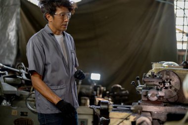 Fabrikada sondaj yapan Asyalı bir işçi. Fabrikadaki sondaj makinesinin yanında profesyonel işçi. Torna makinesinde uçan kıvılcımlarla çalışan metal iç çeliği bitirmek.