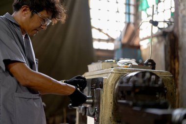 Fabrikada sondaj yapan Asyalı bir işçi. Fabrikadaki sondaj makinesinin yanında profesyonel işçi. Torna makinesinde uçan kıvılcımlarla çalışan metal iç çeliği bitirmek.