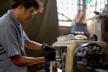 Fabrikada sondaj yapan Asyalı bir işçi. Fabrikadaki sondaj makinesinin yanında profesyonel işçi. Torna makinesinde uçan kıvılcımlarla çalışan metal iç çeliği bitirmek.