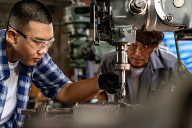 Fabrikada sondaj yapan Asyalı bir işçi. Fabrikadaki sondaj makinesinin yanında profesyonel işçi. Torna makinesinde uçan kıvılcımlarla çalışan metal iç çeliği bitirmek.