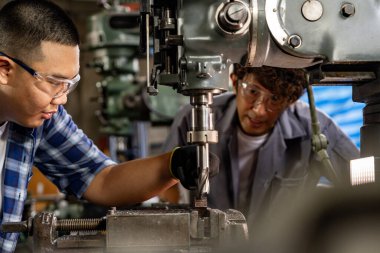 Fabrikada sondaj yapan Asyalı bir işçi. Fabrikadaki sondaj makinesinin yanında profesyonel işçi. Torna makinesinde uçan kıvılcımlarla çalışan metal iç çeliği bitirmek.