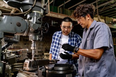 Fabrikada sondaj yapan Asyalı bir işçi. Fabrikadaki sondaj makinesinin yanında profesyonel işçi. Torna makinesinde uçan kıvılcımlarla çalışan metal iç çeliği bitirmek.