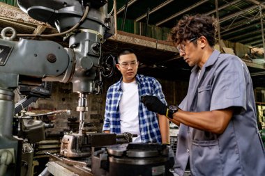 Fabrikada sondaj yapan Asyalı bir işçi. Fabrikadaki sondaj makinesinin yanında profesyonel işçi. Torna makinesinde uçan kıvılcımlarla çalışan metal iç çeliği bitirmek.