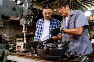 Fabrikada sondaj yapan Asyalı bir işçi. Fabrikadaki sondaj makinesinin yanında profesyonel işçi. Torna makinesinde uçan kıvılcımlarla çalışan metal iç çeliği bitirmek.