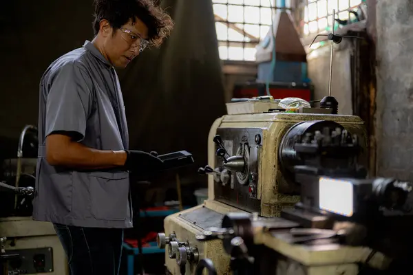 stock image Asian worker in production plant drilling at machine. Professional worker near drilling machine on factory. finishing metal working internal steel surface on lathe grinder machine with flying sparks.