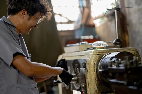 機械で掘削する生産工場のアジアの労働者 工場の鋭い機械の近くの専門の労働者 フライングスパーク付き旋盤グラインダー機の金属加工内部スチール表面仕上げ — ストック写真