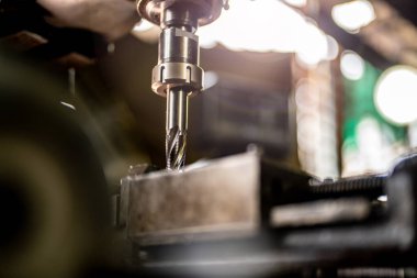 Metal matkap ucunu kapatın çelik kalıpta delikler açmak için pozisyonunuzu koruyun. Metal endüstrisi. CNC değirmen makinesinde metal plaka parçaları ile değirmen işlemi. Fabrika zemin değirmen işlemleri.