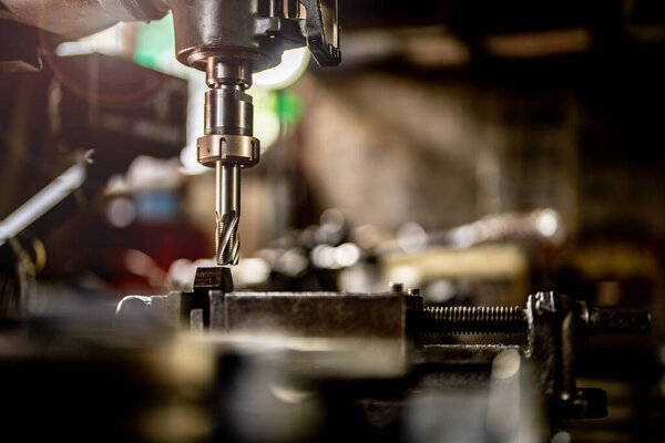 close up metal drill bit stay position for make holes in steel mold. Metal industry. milling process with metal plate parts on CNC milling machine. shop floor milling operation by milling machine.