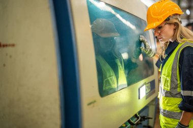 Fabrika mühendisi kadın kontrol paneli anahtarı için kendine güveniyor. İşçi, sanayi fabrikasındaki ağır makinede çalışıyor. Makine teçhizatı fabrika teknolojisiyle. akıllı endüstri çalışanı.