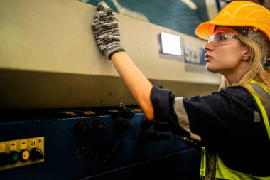 Fabrika mühendisi kadın kontrol paneli anahtarı için kendine güveniyor. İşçi, sanayi fabrikasındaki ağır makinede çalışıyor. Makine teçhizatı fabrika teknolojisiyle. akıllı endüstri çalışanı.