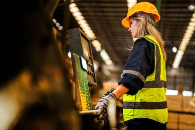Fabrika mühendisi kadın kontrol paneli anahtarı için kendinden emin duruyor. İşçi, sanayi fabrikasındaki ağır makinede çalışıyor. İşçi, ham ahşap kerestelerini kontrol ediyor. akıllı endüstri çalışanı.