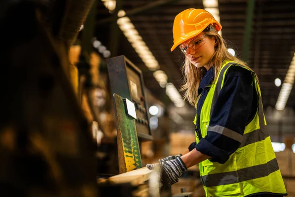 Factory engineer woman standing confident to control panel switch. Worker works at heavy machine at industry factory. worker checking timber of raw wood material. smart industry worker operating.