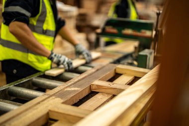 Karanlık depo endüstrisinde ahşap temizleyen eller. Takım çalışanı marangoz, güvenlik üniforması ve sıkı bir şapka giyer atölyede ahşap ürünlerin kalitesini kontrol eder ve çalışır..