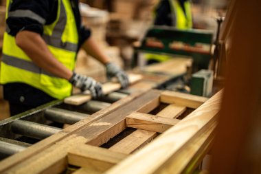 Karanlık depo endüstrisinde ahşap temizleyen eller. Takım çalışanı marangoz, güvenlik üniforması ve sıkı bir şapka giyer atölyede ahşap ürünlerin kalitesini kontrol eder ve çalışır..