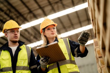 İşçi erkek ve kadın mühendisler depoda kereste odunlarını inceliyor. Akıllı endüstri çalışanı kavramı. Ahşap fabrikaları ağaç damak üretir..