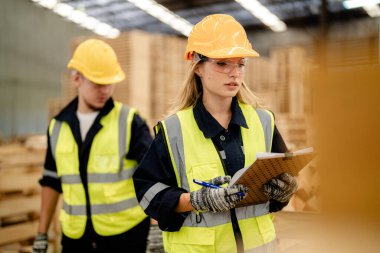 İşçi erkek ve kadın mühendisler depoda kereste odunlarını inceliyor. Akıllı endüstri çalışanı kavramı. Ahşap fabrikaları ağaç damak üretir..