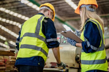 İşçi marangozlar odunları kesmek için makinelerde çalışıyorlar. Erkek ve kadın bir atölyede ahşap işçiliği yapıyorlar. Marangoz aletleri ya da elektrikli makinelerle çalışan iki usta ya da tamirci.. 