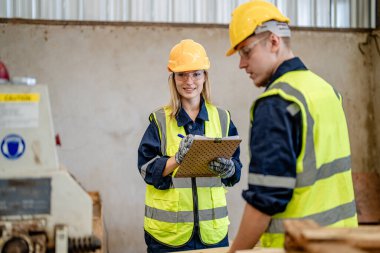 İşçi marangozlar odunları kesmek için makinelerde çalışıyorlar. Erkek ve kadın bir atölyede ahşap işçiliği yapıyorlar. Marangoz aletleri ya da elektrikli makinelerle çalışan iki usta ya da tamirci.. 