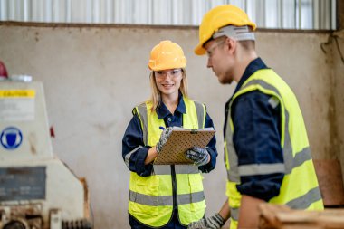 İşçi marangozlar odunları kesmek için makinelerde çalışıyorlar. Erkek ve kadın bir atölyede ahşap işçiliği yapıyorlar. Marangoz aletleri ya da elektrikli makinelerle çalışan iki usta ya da tamirci.. 