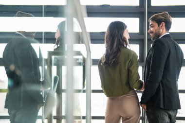 İş adamları iş yerinde eğleniyor ve sohbet ediyorlar. Erkek ve bayan meslektaşlar ortak çalışma alanında tanışmaktan hoşlanırlar. İş arkadaşlarım ofiste projeyi tartışıyorlar..