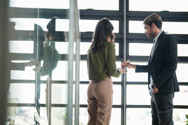 İş adamları iş yerinde eğleniyor ve sohbet ediyorlar. Erkek ve bayan meslektaşlar ortak çalışma alanında tanışmaktan hoşlanırlar. İş arkadaşlarım ofiste projeyi tartışıyorlar..