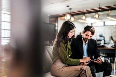 İş yerindeki işadamları konuşuyor. Erkek ve bayan meslektaşlar rahatlamayı ve koltukta oturmayı severler. İş arkadaşları ofiste projeyi tartışıyor. Görevdeki gençlerden oluşan bir takım.