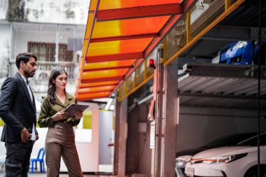 İş adamına araba satan profesyonel bir satış elemanı. Araba satışı. Garaj Otoparkı Mağazası 'ndaki İşadamı Alıcı' ya öneriler veriyor. Araba satıcısı satış danışmanı..