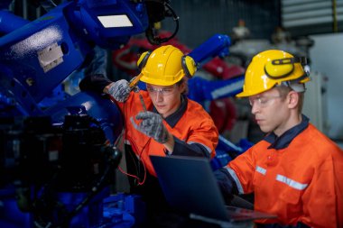 Erkek mühendis bir fabrikadaki otomatik robotik kol makinesini tamir ediyor. İşçi otomatik robot el makinesini kontrol ediyor ve onarıyor. Teknisyen, tamir makinesini kontrol et..