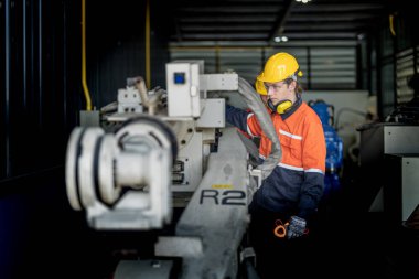 Makinenin durumunu kontrol eden mühendis CNC fabrikasındaki bazı aletleri vidalamak için İngiliz anahtarı kullanmış. Güvenlik gözlüğü ve kask takan bir işçi. Bakım ve onarım kavramı.