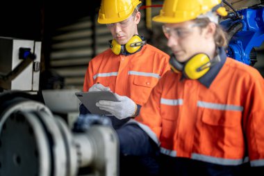 Erkek mühendis bir fabrikadaki otomatik robotik kol makinesini tamir ediyor. İşçi otomatik robot el makinesini kontrol ediyor ve onarıyor. Teknisyen, tamir makinesini kontrol et..