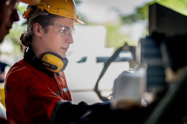 Makinenin durumunu kontrol eden mühendis CNC fabrikasındaki bazı aletleri vidalamak için İngiliz anahtarı kullanmış. Güvenlik gözlüğü ve kask takan bir işçi. Bakım ve onarım kavramı.