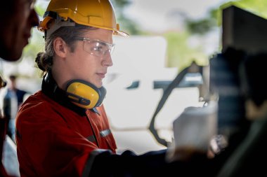 Makinenin durumunu kontrol eden mühendis CNC fabrikasındaki bazı aletleri vidalamak için İngiliz anahtarı kullanmış. Güvenlik gözlüğü ve kask takan bir işçi. Bakım ve onarım kavramı.