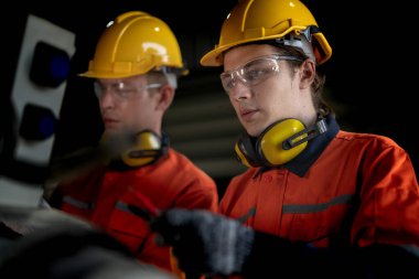 Makinenin durumunu kontrol eden mühendis CNC fabrikasındaki bazı aletleri vidalamak için İngiliz anahtarı kullanmış. Güvenlik gözlüğü ve kask takan bir işçi. Bakım ve onarım kavramı.