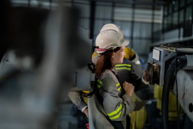 Mühendisler ağır makine robot kolunu kontrol ediyorlar. Çeşitli Endüstriyel Robot Mühendisleri Ekibi Makine etrafında toplandı. Profesyonel Makine İşlemcileri elektrikli robotu parlak dijital panelde tamir ederler.