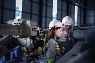 Mühendisler ağır makine robot kolunu kontrol ediyorlar. Çeşitli Endüstriyel Robot Mühendisleri Ekibi Makine etrafında toplandı. Profesyonel Makine İşlemcileri elektrikli robotu parlak dijital panelde tamir ederler.