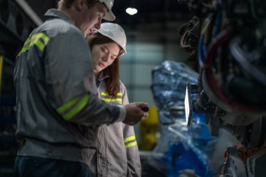 Mühendisler ağır makine robot kolunu kontrol ediyorlar. Çeşitli Endüstriyel Robot Mühendisleri Ekibi Makine etrafında toplandı. Profesyonel Makine İşlemcileri elektrikli robotu parlak dijital panelde tamir ederler.