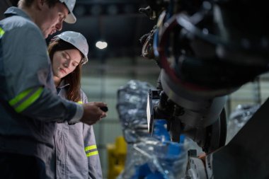 Mühendisler ağır makine robot kolunu kontrol ediyorlar. Çeşitli Endüstriyel Robot Mühendisleri Ekibi Makine etrafında toplandı. Profesyonel Makine İşlemcileri elektrikli robotu parlak dijital panelde tamir ederler.