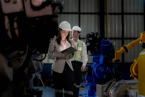 ビジネス女性と男性が会って新しいマシンロボットをチェックします 倉庫産業機械で歩いているエンジニア ビジネス交渉の概念および技術 女性は男性を提示するためにスマートタブレットを使用しています — ストック写真