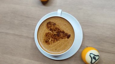 Ahşap arka planda latte sanatıyla bir fincan kahve.