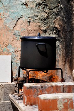 Ateşin üstünde siyah tencere yemeği pişiriyor.